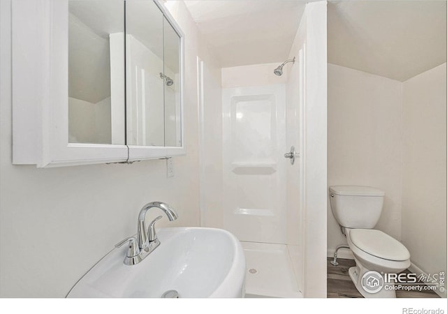 bathroom featuring toilet, sink, hardwood / wood-style floors, and walk in shower