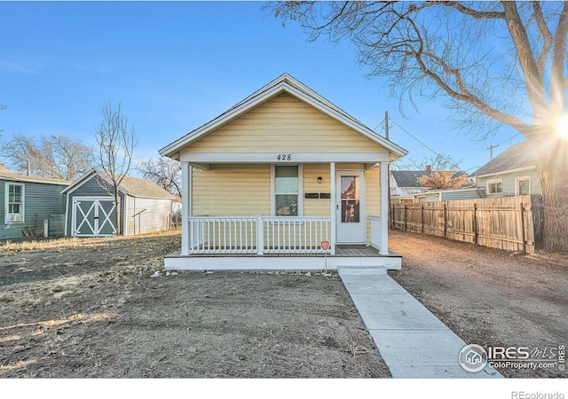 bungalow featuring covered porch and a storage unit