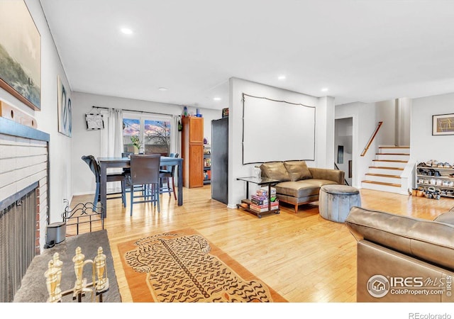 living room with a brick fireplace and hardwood / wood-style floors