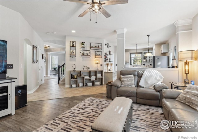 living room with ornate columns, ceiling fan, and light wood-type flooring