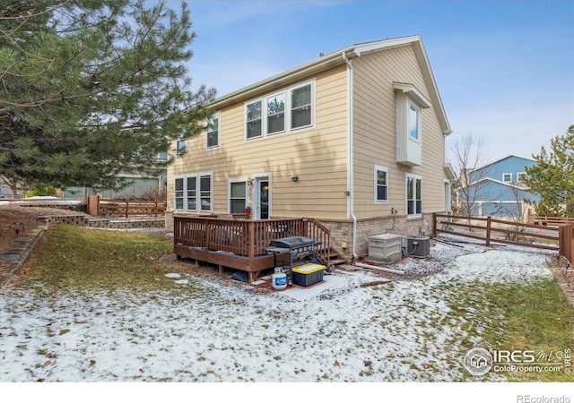 snow covered property featuring cooling unit and a deck