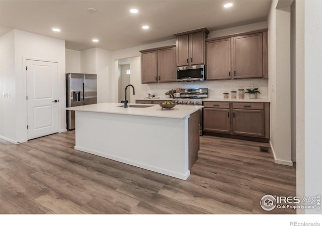 692 Galloway Dr, Johnstown, CO 80534 - kitchen featuring stainless steel appliances, a sink, decorative backsplash, dark wood-style floors, and a center island with sink