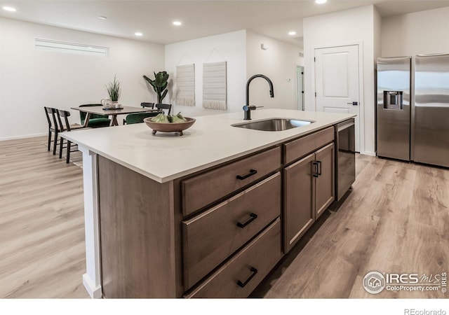 692 Galloway Dr, Johnstown, CO 80534 - kitchen featuring stainless steel fridge with ice dispenser, a sink, light wood finished floors, a center island with sink, and recessed lighting