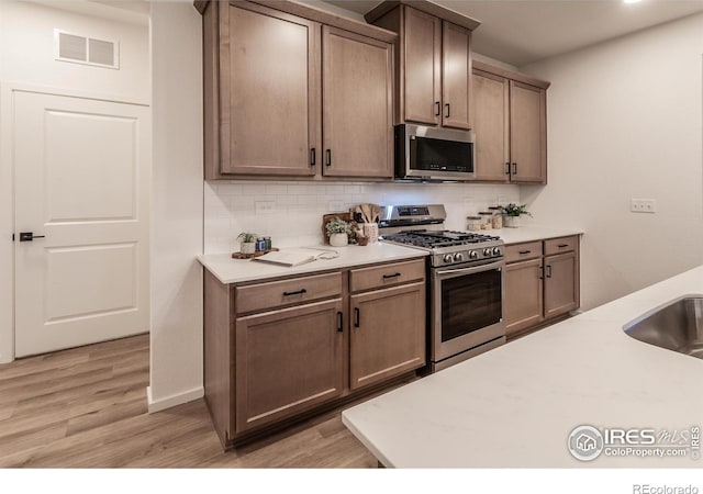 692 Galloway Dr, Johnstown, CO 80534 - kitchen featuring appliances with stainless steel finishes, tasteful backsplash, light countertops, and light wood finished floors