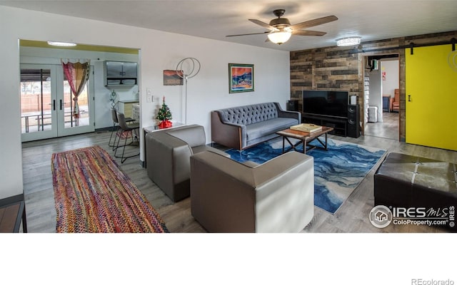 living room featuring french doors, ceiling fan, a barn door, and hardwood / wood-style floors