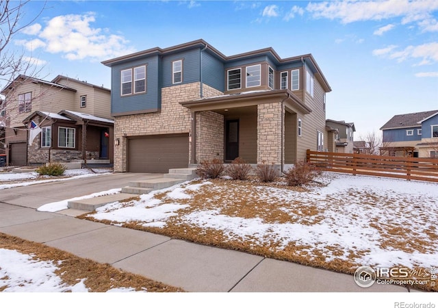 view of front of home with an attached garage, stone siding, fence, and concrete driveway