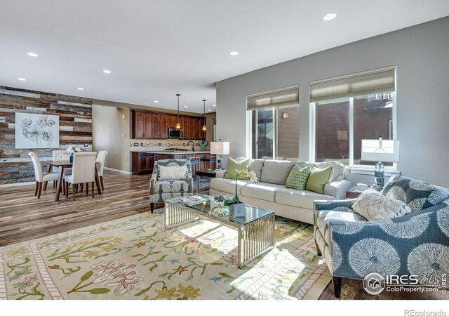 living room featuring an accent wall, light wood finished floors, and recessed lighting