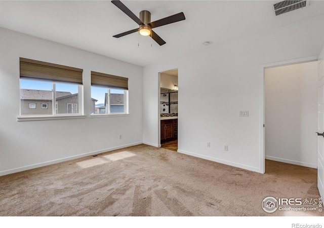 unfurnished bedroom featuring ensuite bathroom, light carpet, a ceiling fan, visible vents, and baseboards