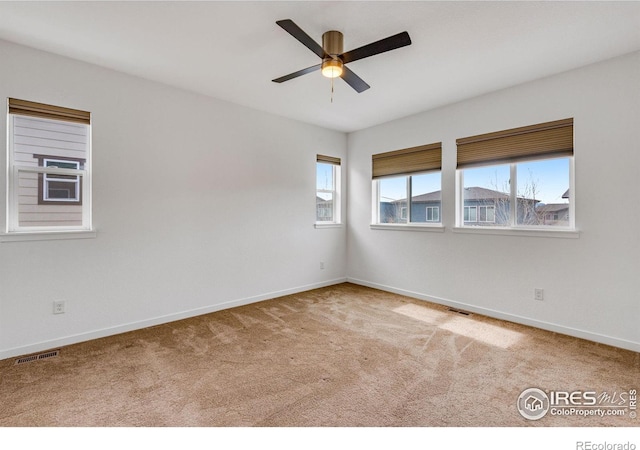 carpeted empty room with baseboards, visible vents, and ceiling fan
