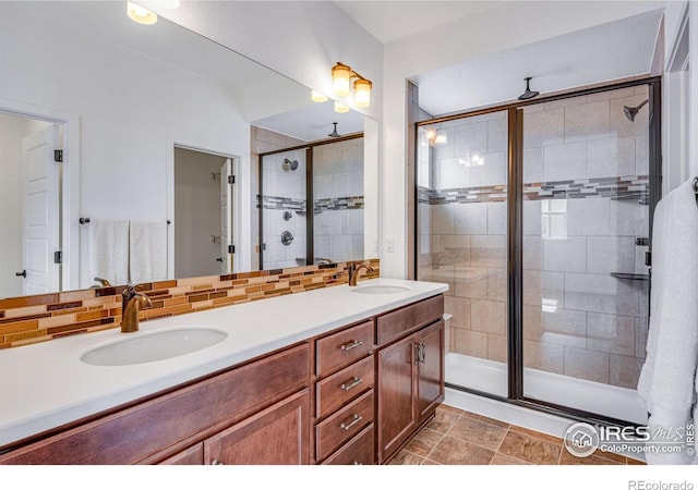 full bathroom with a sink, a shower stall, decorative backsplash, and double vanity