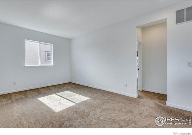 carpeted spare room featuring baseboards and visible vents