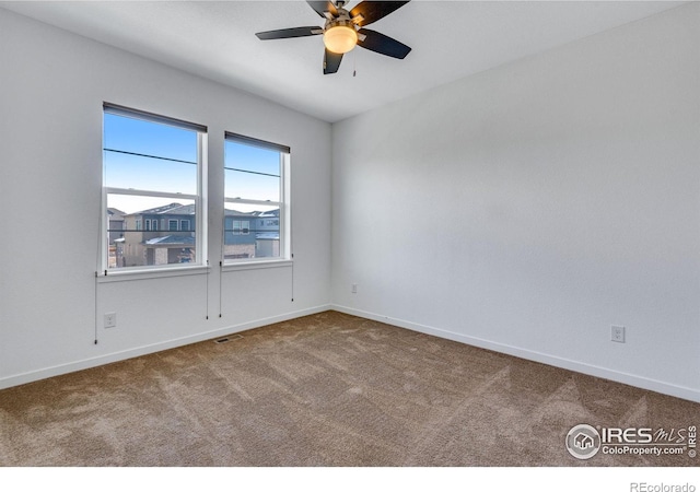 spare room with carpet floors, ceiling fan, and baseboards