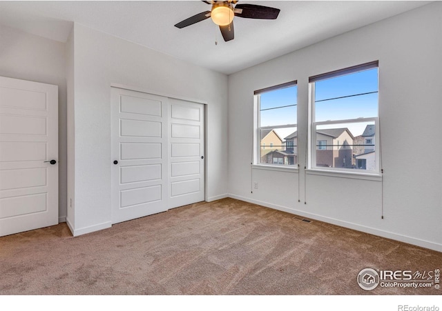 unfurnished bedroom featuring ceiling fan, light carpet, visible vents, baseboards, and a closet