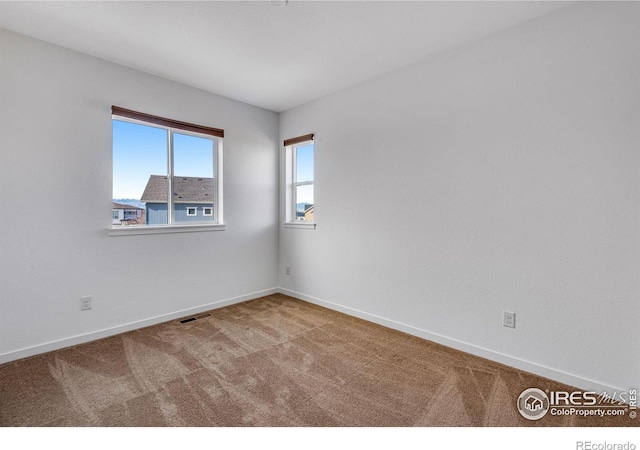 carpeted spare room with baseboards and visible vents