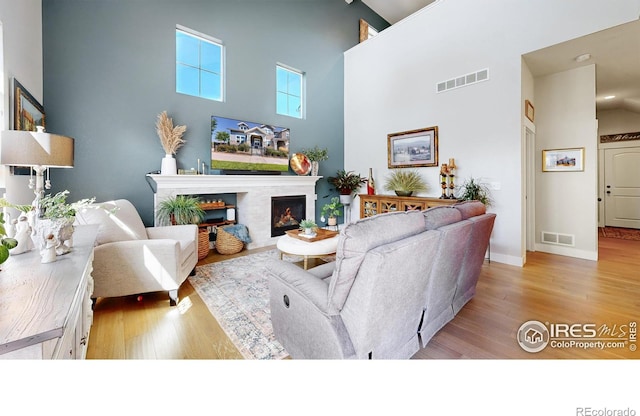 living room with a towering ceiling and light hardwood / wood-style flooring