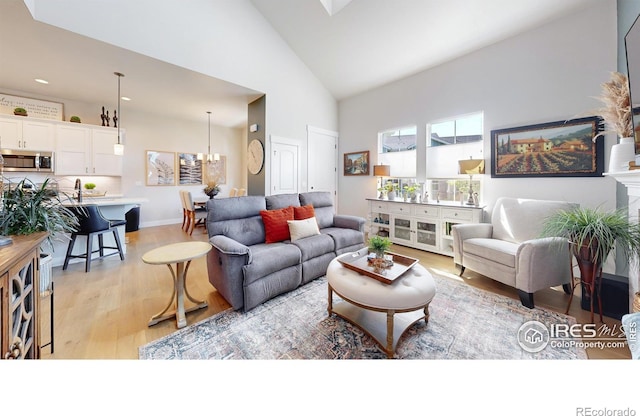 living room featuring light hardwood / wood-style flooring, high vaulted ceiling, and a chandelier