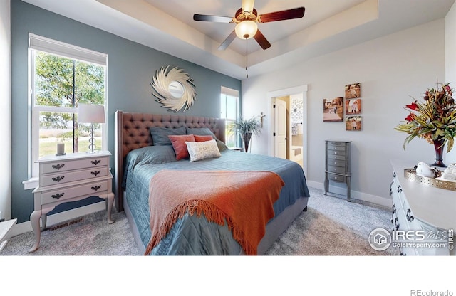 carpeted bedroom featuring connected bathroom, ceiling fan, and a tray ceiling