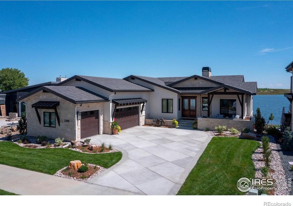 view of front of home featuring a front lawn, a garage, and a water view