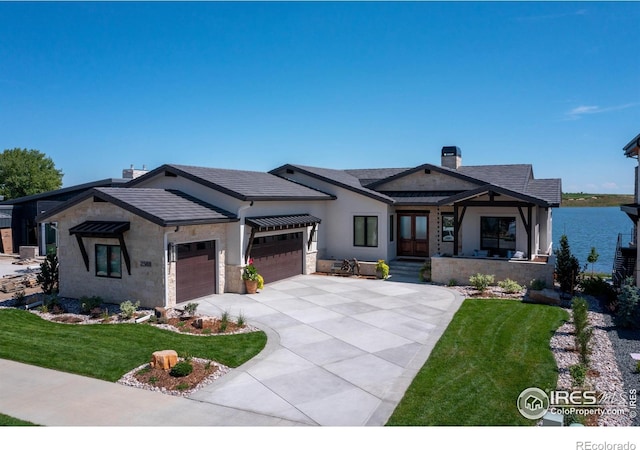 view of front of home featuring a front lawn, a garage, and a water view