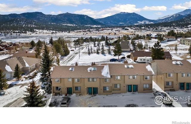 snowy aerial view featuring a mountain view and a residential view