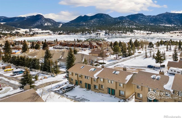 snowy aerial view featuring a mountain view and a residential view