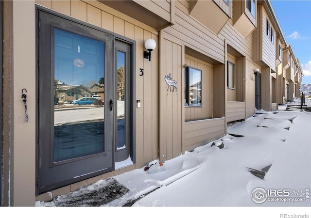 snow covered property entrance with board and batten siding