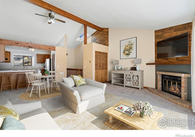 living room featuring light carpet, a ceiling fan, vaulted ceiling with beams, and a fireplace