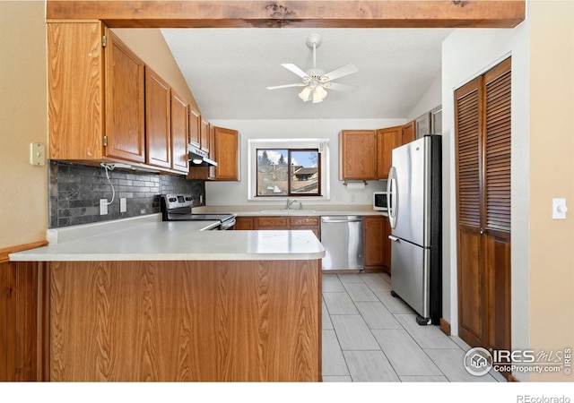 kitchen featuring under cabinet range hood, vaulted ceiling with beams, a peninsula, and appliances with stainless steel finishes