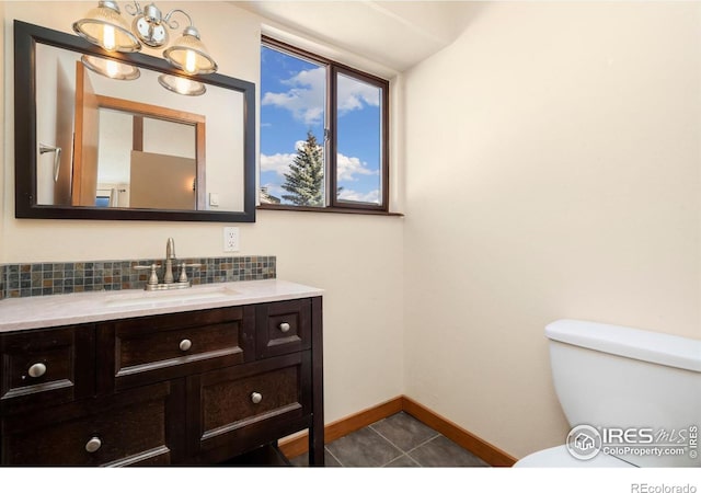 bathroom with tasteful backsplash, tile patterned flooring, baseboards, toilet, and vanity