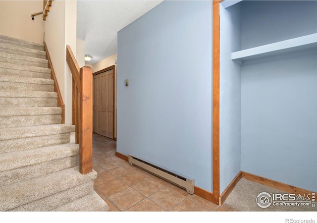 stairway featuring tile patterned floors, a textured ceiling, baseboards, and a baseboard radiator