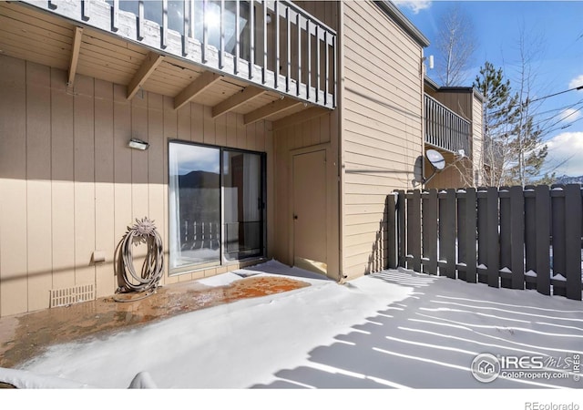 snow covered property entrance featuring crawl space, a patio, a balcony, and fence