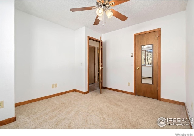 unfurnished room featuring baseboards, a textured ceiling, and carpet