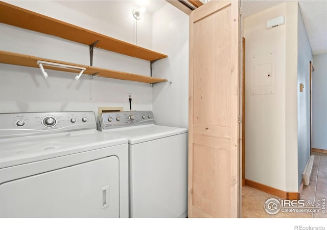 laundry area with baseboards, washing machine and clothes dryer, laundry area, electric panel, and light tile patterned flooring