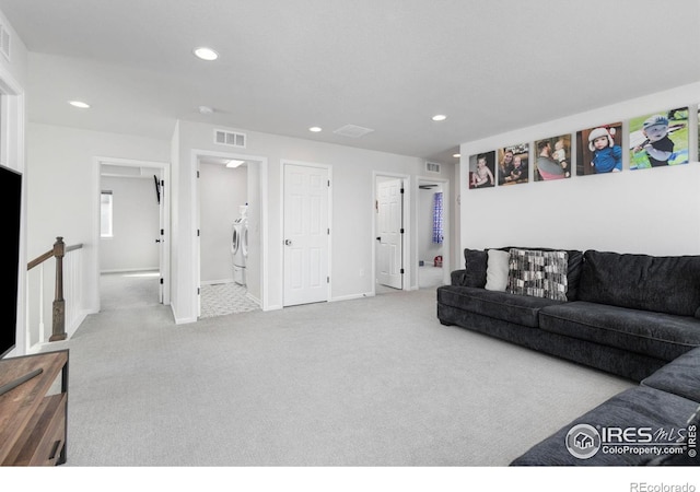 carpeted living room featuring washing machine and dryer