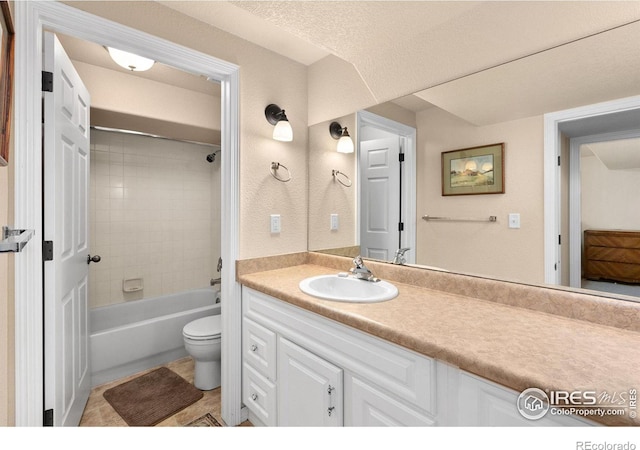 full bathroom with vanity, toilet, tiled shower / bath combo, and a textured ceiling