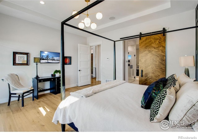 bedroom with hardwood / wood-style floors, a barn door, and a notable chandelier