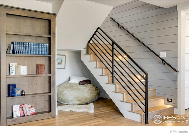 staircase with hardwood / wood-style flooring and wooden walls