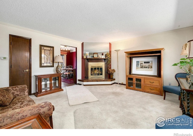 carpeted living room featuring ornamental molding, a textured ceiling, and a glass covered fireplace