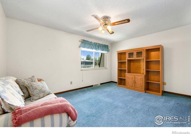 unfurnished room featuring a textured ceiling, carpet, a ceiling fan, and baseboards