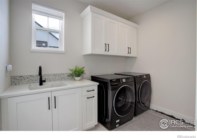 washroom featuring cabinets, washing machine and dryer, and sink