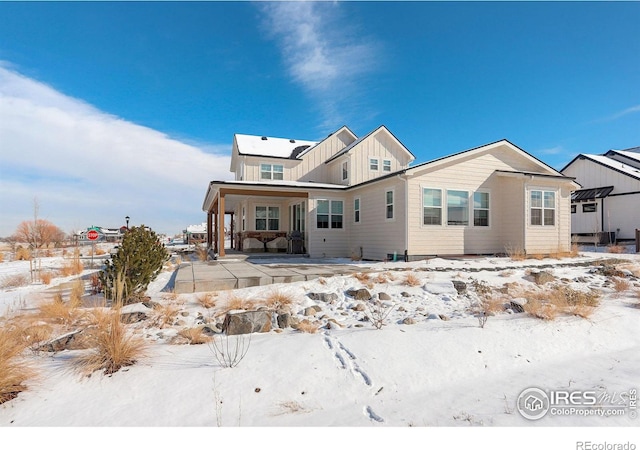 snow covered rear of property featuring covered porch and a pergola