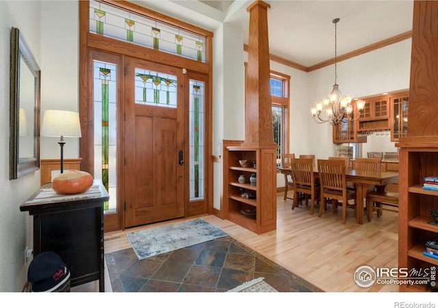 entrance foyer with hardwood / wood-style floors, crown molding, an inviting chandelier, and plenty of natural light