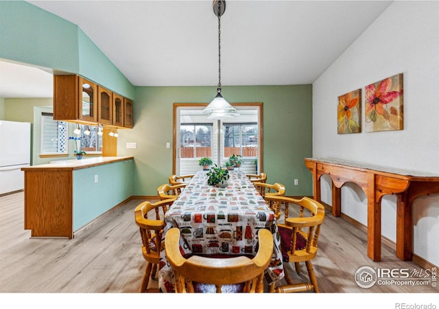 dining room with light hardwood / wood-style flooring and lofted ceiling