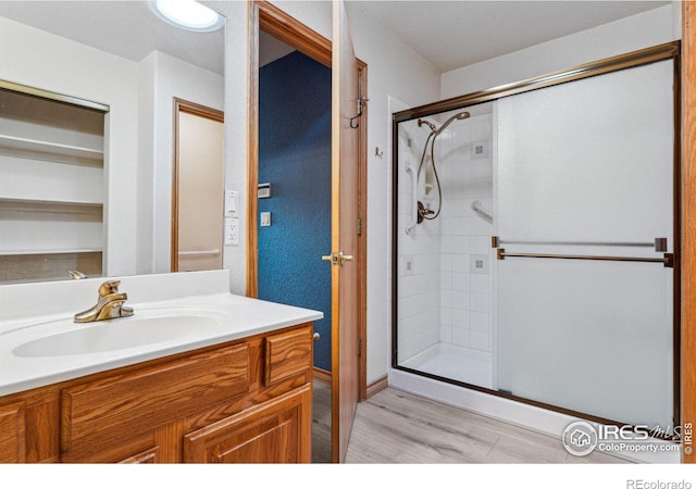 bathroom featuring hardwood / wood-style floors, vanity, and a shower with door