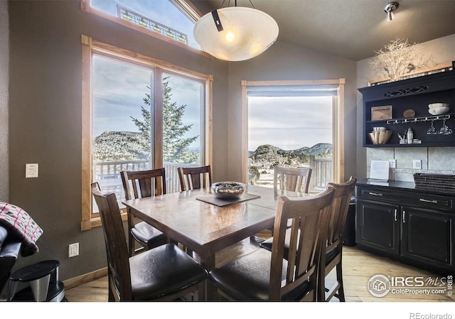 dining area featuring a mountain view, light hardwood / wood-style floors, and plenty of natural light