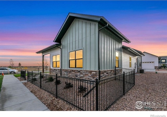 3425 Green Lake Dr, Fort Collins, CO 80524 - property exterior at dusk featuring stone siding, board and batten siding, fence, and central air condition unit