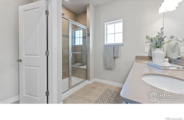 bathroom featuring a sink, baseboards, tile patterned floors, double vanity, and a stall shower