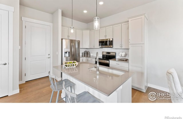 kitchen with stainless steel appliances, light wood-type flooring, backsplash, and a kitchen breakfast bar