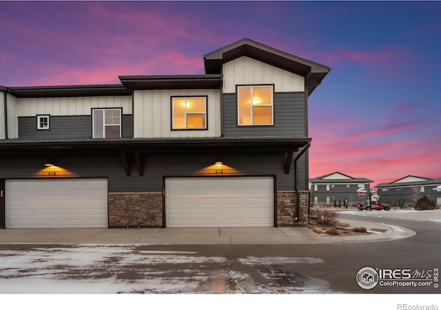 townhome / multi-family property with a garage, stone siding, and board and batten siding