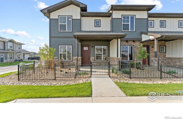 view of front of property featuring stone siding, fence, and board and batten siding